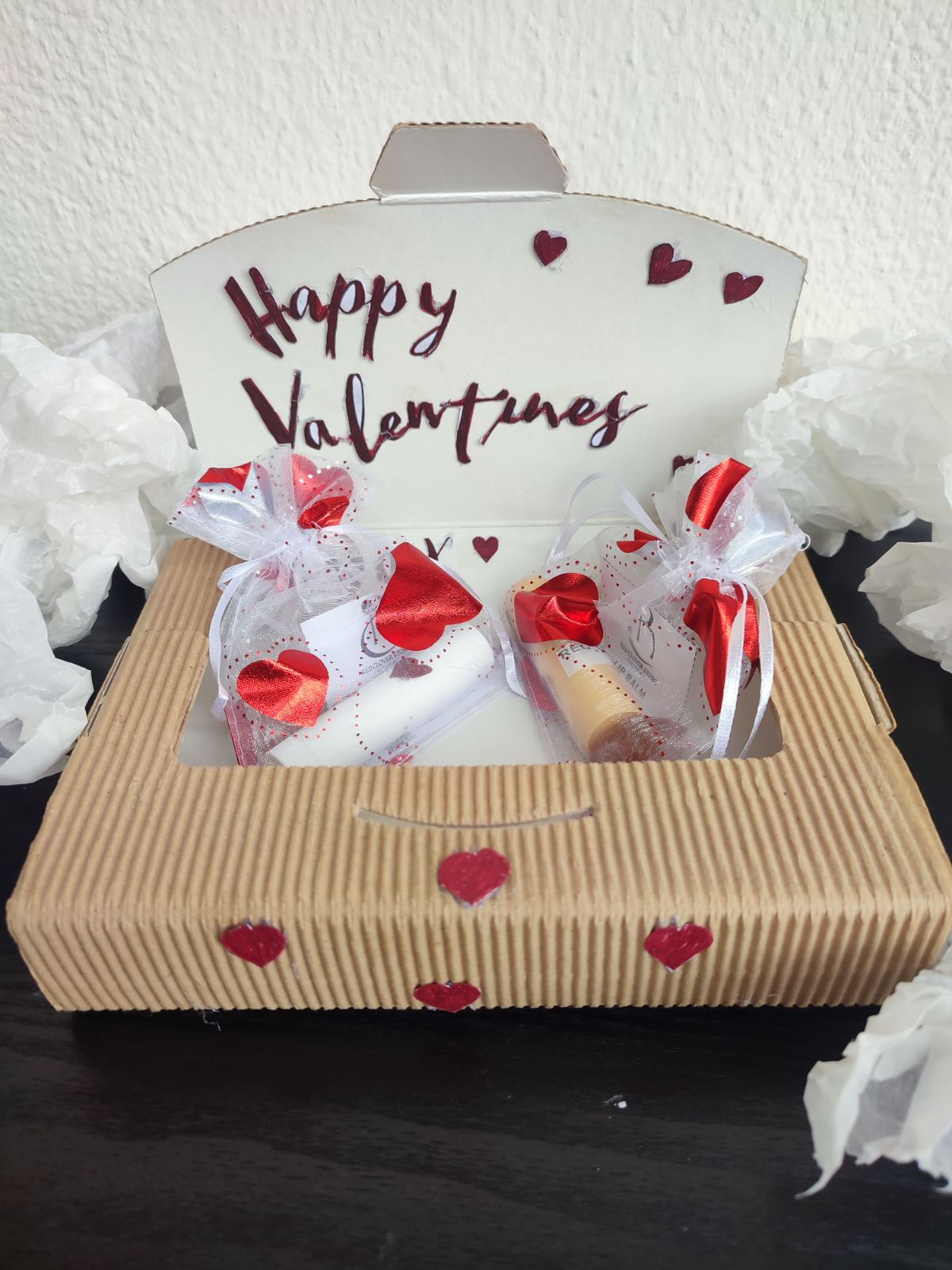 Eco-friendly gift box featuring two organic beeswax lip balms in festive white organza bags with red hearts
