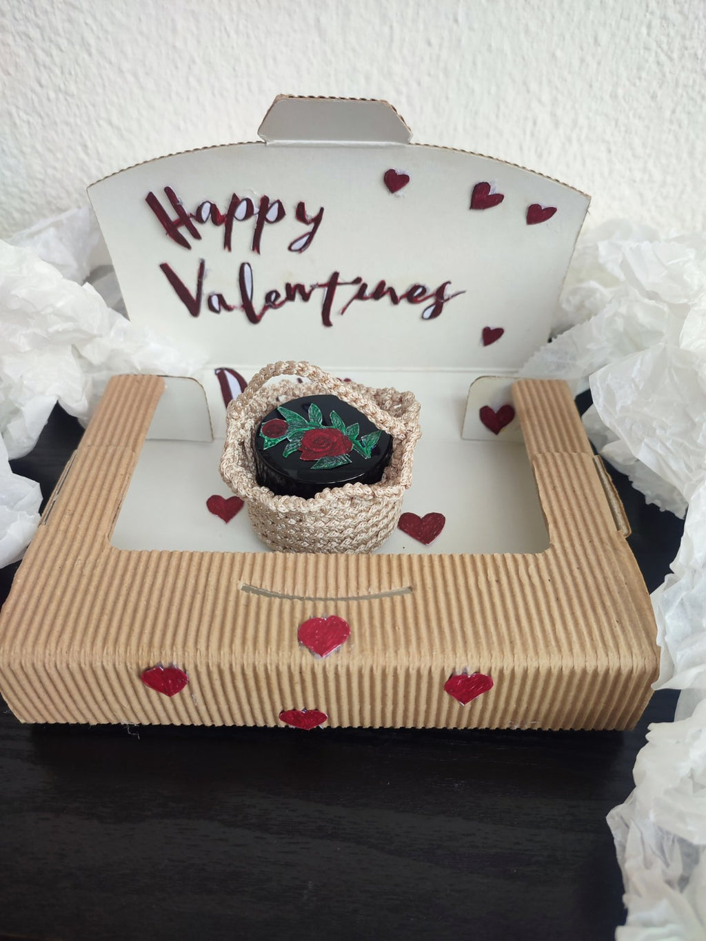 Open Valentine's gift box containing a herbal salve jar nestled in a handmade beige crocheted basket.